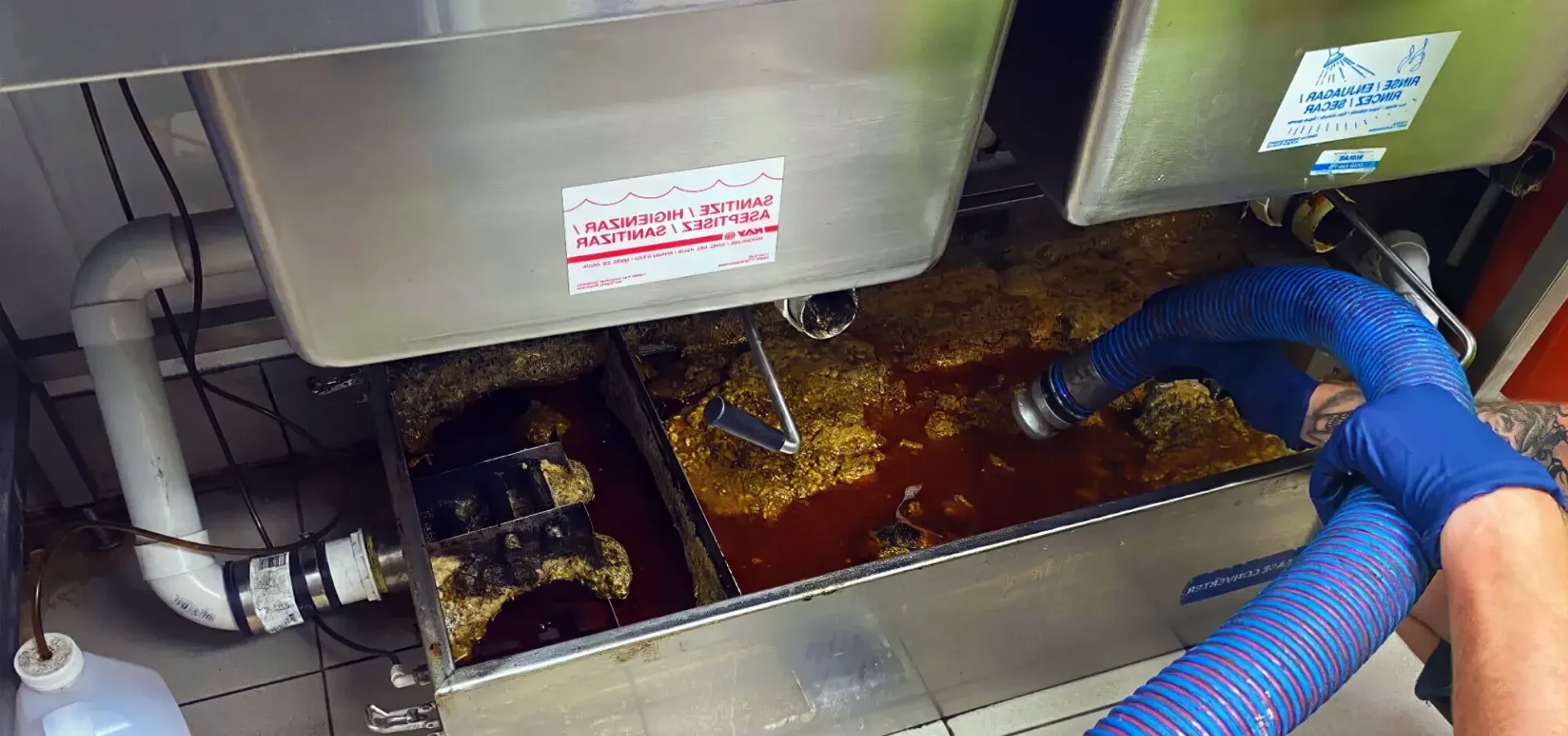Cleaning commercial kitchen grease trap with hose